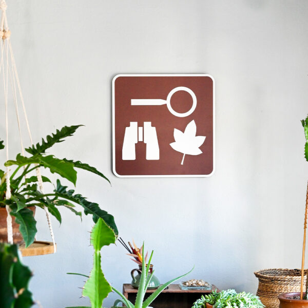 Nature observation sign hung up on green house wall.