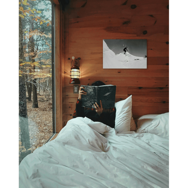 A Mt Hood Ski sign hung up on the wall above a bed in a cabin.