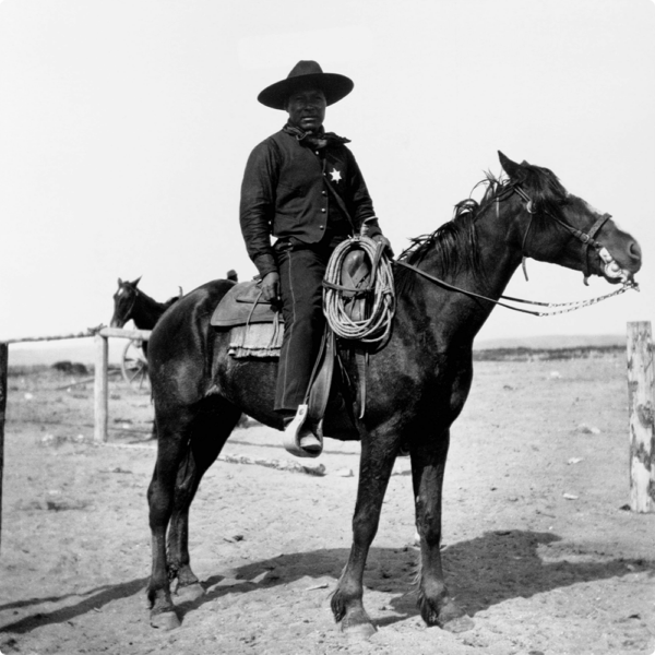 A Black Sheriff with a hat on sitting on a horse.